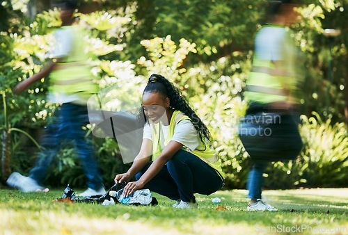 Image of Volunteer, plastic and black woman cleaning park as community service for recycling and pollution. Ngo person happy to help group with bottle, dirt and trash bag outdoor in green nature environment