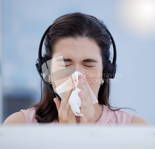 Image of Customer service, covid and blowing nose with a woman consultant working in a call center while sick. CRM, telemarketing and cold or flu with a female sneezing while consulting using a headset