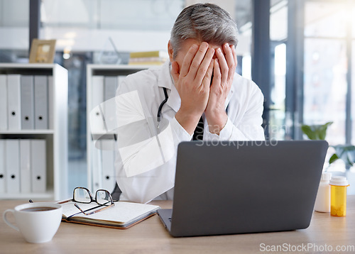 Image of Doctor, burnout and man with stress in hospital feeling depressed while working on laptop. Mental health, depression and medical professional or physician with headache, pain and anxiety in clinic.