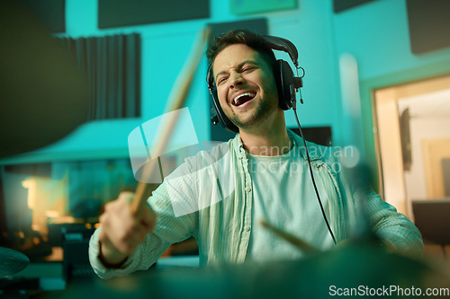 Image of Musician, headphones and man drummer playing in a recording studio for production of a song. Musical artist, drums and male with a passion for music with a percussion instrument for entertainment.