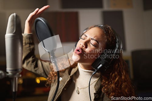 Image of Music, singing and black woman recording in studio in home, streaming with microphone, headphones and talent. Technology, art and creative influencer or musician with song stream for record label.