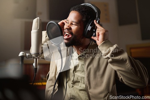 Image of Music, streaming and man recording in studio in home, singing into microphone with headphones and talent. Technology, art and creative influencer or musician with live stream song for record label.