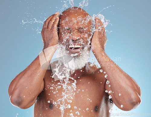 Image of Water splash, skincare and black man isolated on blue background for face cleaning, beauty and using hands. Happy senior model or person with facial wash or hygiene for dermatology in studio action