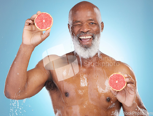 Image of Black man, portrait smile and fruit for nutrition, vitamin C or skincare hydration against a blue studio background. Happy African American male smiling and holding grapefruit for health and wellness