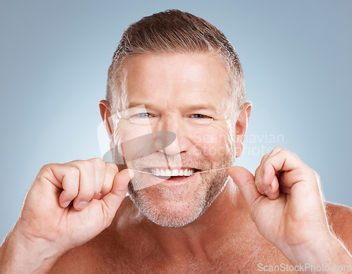Image of Floss, portrait and man with dental health for fresh breath, hygiene and cleaning teeth against blue studio background. Oral health, male and string for mouth, morning routine or grooming on backdrop