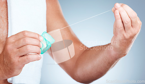 Image of Hands, dental and floss product in studio isolated on a blue background for oral hygiene. Health, wellness and senior man model holding container with thread for flossing, cleaning and teeth care.