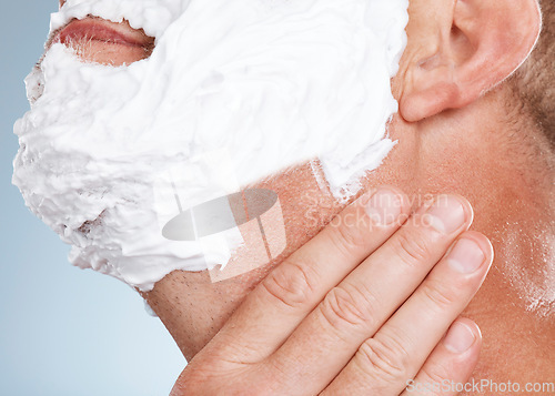 Image of Face, shaving cream and hands of man in studio isolated on a blue background for hair removal. Skincare, cleaning and grooming male model with gel or foam to shave for aesthetics, health and wellness