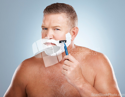 Image of Portrait, shaving cream and man with razor in studio isolated on a blue background for hair removal. Face, skincare and mature male model with facial foam to shave for aesthetics, health or wellness