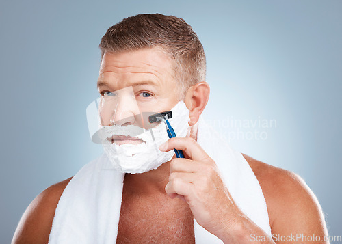 Image of Face, shaving cream and man with razor in studio isolated on a blue background for hair removal. Portrait, skincare and mature male model with facial foam to shave for aesthetics, health or wellness