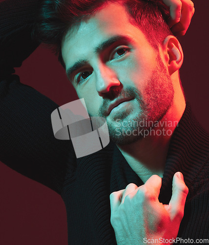 Image of Man, fashion and face portrait in studio with red light for clothes, beauty and luxury style on dark background. Aesthetic model person hand on turtle neck for art, cosmetics and inspiration for men