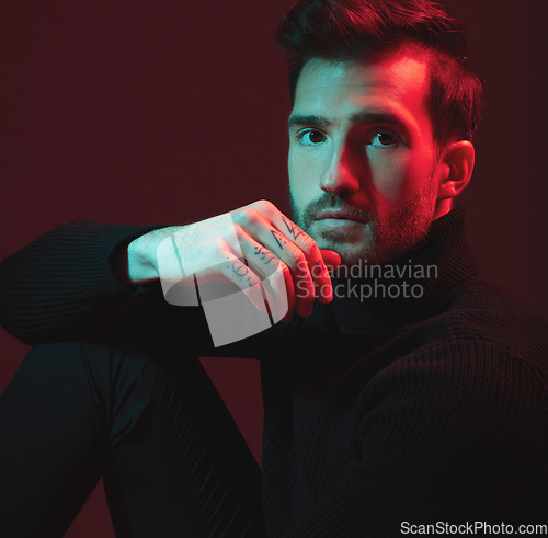 Image of Man, fashion model and portrait of a model with beauty and lighting shadow in a studio. Black background, isolated and color lights of a young person with a hand tattoo for creative aesthetic