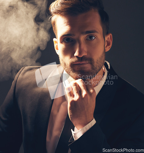Image of Portrait, smoke and man in suit, fashion and executive with confidence on dark studio background. Face, male leader and elegant gentleman with vintage clothes, stylish outfit and smoking on backdrop