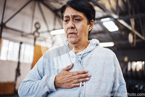 Image of Senior woman with chest pain or injury in the gym after a intense workout or training. Healthcare, sick and elderly lady in retirement with asthma or breathing problem during exercise in sport center