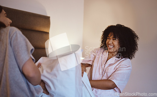 Image of Women, laughing or pillow fight in house, home or hotel bedroom in fun game, energy activity or sleepover challenge. Smile, happy or play fighting friends and linen product, bedding or bonding comedy