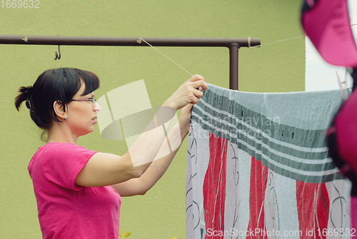 Image of Woman hang laundry on clothesline strings