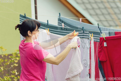 Image of Woman hang laundry on clothesline strings