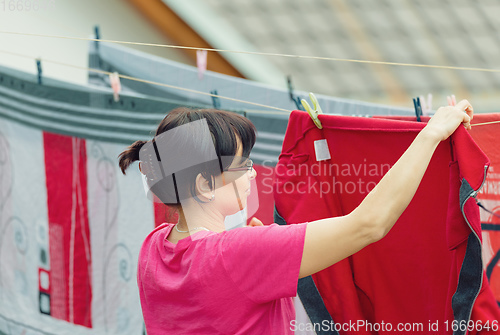 Image of Woman hang laundry on clothesline strings