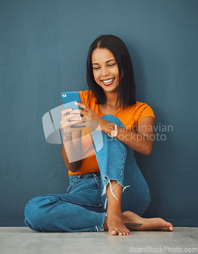 Image of Happiness, black woman on floor and smartphone for connection, smile and communication on dark studio background. Female, lady and cellphone for typing, texting and social media for online reading