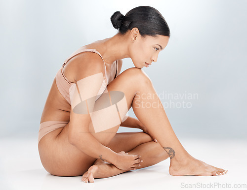 Image of Body, woman on floor and skincare in a bikini, cosmetics or confident on grey studio background. Female, lady on ground or beauty with wellness, self care or natural health with grooming and backdrop