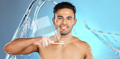 Image of Dental, portrait and man brushing teeth in water splash, studio and mockup on blue background. Oral, hygiene and male teeth model with brush for mouth, cleaning and whitening product while isolated