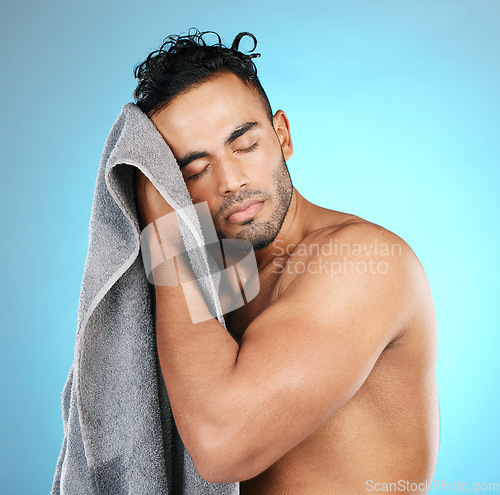 Image of Man, towel and dry hair in studio after shower, cleaning and washing for beauty routine on isolated blue background. Bathroom, haircare and male model relax with wellness, body care and grooming