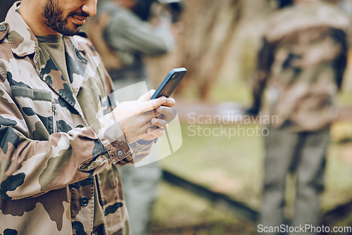 Image of Chat, typing and man with a phone in the army for communication, social media and contact. Website, email and person reading a message on a mobile app while playing paintball on a field with friends