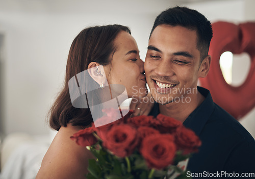 Image of Love, flowers and valentines day with a couple kissing in their home, in celebration of romance. Dating, rose bouquet or surprise with a man and woman in a house to kiss while bonding in intimacy