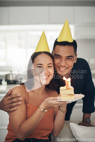 Image of Portrait, birthday cake and smile with a couple in their home, holding dessert for celebration in party hats. Love, candle or romance with a young man and woman celebrating together in their house