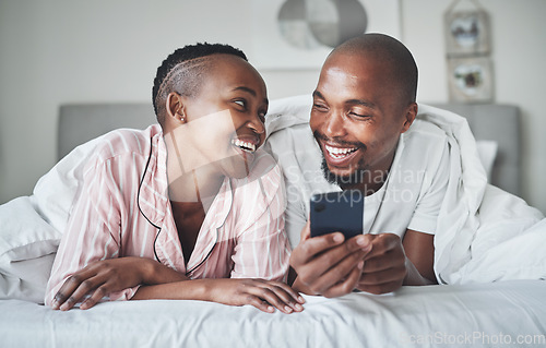 Image of Phone, social media and morning with a black couple in the bedroom together to relax on a bed in their home. Mobile, meme or contact with a man and woman browsing the internet, relaxing or bonding