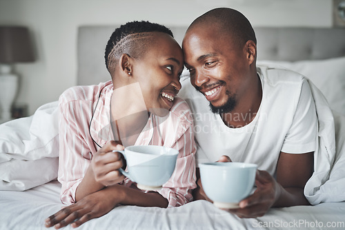 Image of Coffee, bedroom and morning with a black couple together on a bed in their home to relax on the weekend. Love, tea or early with a happy young man and woman relaxing while bonding in their house