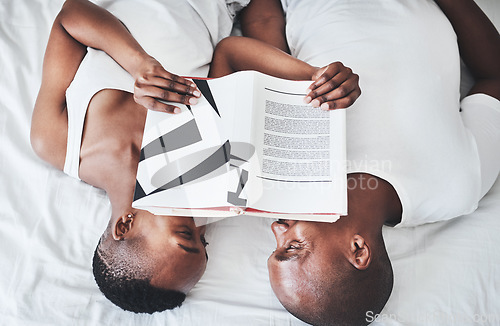 Image of Book, reading and overhead with a black couple in bed, lying together in the morning in their home. Read, books or love with a man and woman bonding in the bedroom of their house from above