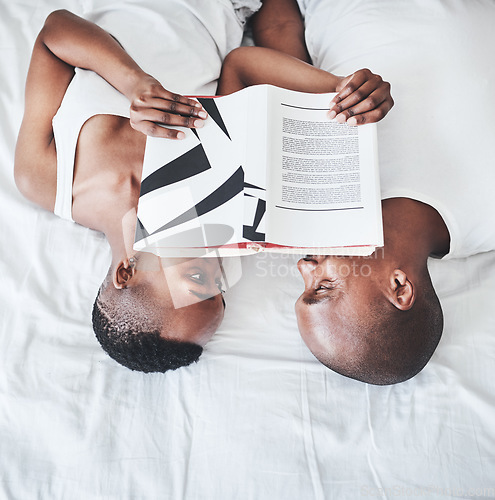 Image of Books, reading and overhead with a black couple in bed, lying together in the morning in their home. Read, book or love with a man and woman bonding in the bedroom of their house from above