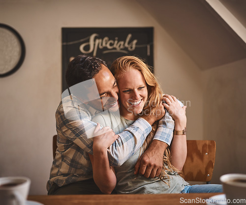 Image of Happy couple, hug and smile in date at cafe for romance, embrace or relationship happiness indoors. Young man hugging woman and smiling for fun love or dining spending bonding time at restaurant