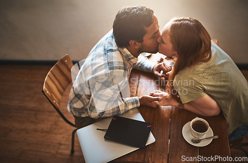 Image of Cafe, kiss and couple on a coffee shop date together holding hands with love and care. Morning, restaurant above and happy young people with tea dating with happiness at a table with a hot drink