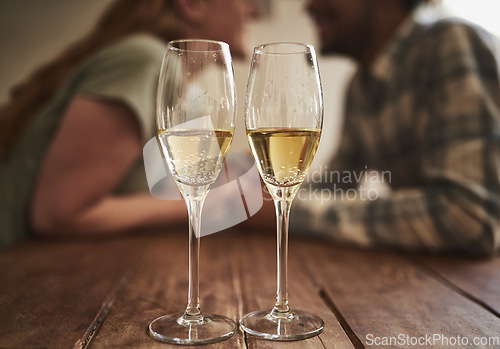 Image of Champagne, glass and love on valentines day with a couple kissing in the background of a restaurant for romance. Alcohol, drink or dating with a man and woman sharing a kiss on a romantic date