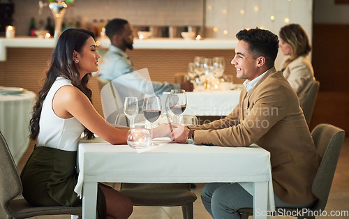 Image of Couple in restaurant for dinner, holding hands and romantic date on Valentines day, love and celebrate holiday. Commitment, interracial relationship and man with woman, trust, support and celebration