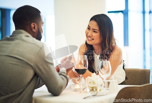 Image of Wine, date and interracial couple holding hands for fine dining, restaurant or valentines celebration together. Black man, asian woman and alcohol glasses for romance, wealth or luxury anniversary