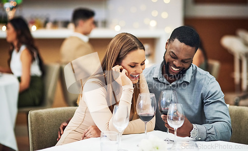 Image of Date, laughing and interracial couple with wine in fine dining, luxury restaurant or valentines celebration together. Funny black man, happy woman and alcohol glasses for romance, rich or anniversary