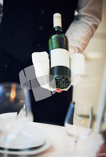 Image of Waiter, table and server hand with wine and hospitality holding alcohol bottle. Bartender, drink and service of a barman at a fine dining restaurant with staff hands and glasses for drinking