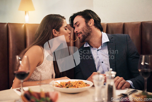 Image of Love, kiss and spaghetti with couple in restaurant sharing for romance, valentines day and date. Bonding, smile and celebration with man and woman with pasta at table for fine dining, wine and cute