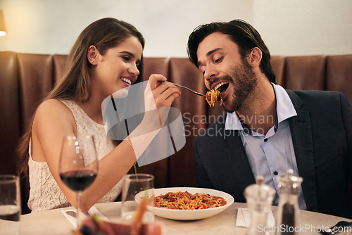 Image of Romantic, date and woman feeding man spaghetti for dinner, supper and fine dining at a restaurant together. Couple, cute and happy lovers enjoying food, pasta and wine for valentines day