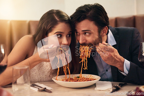 Image of Hungry, restaurant and couple eating spaghetti for love, crazy fun and sharing plate on valentines date celebration. Happy people with pasta food for anniversary, dinner or fine dining experience