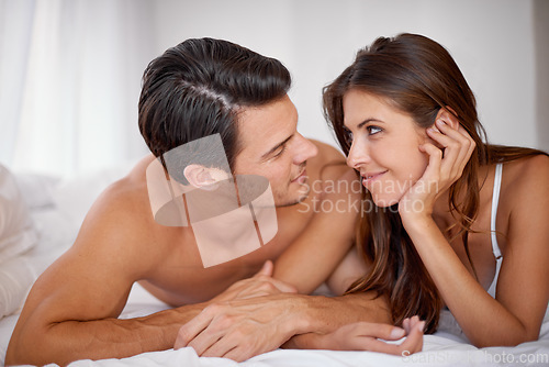 Image of Intimate, romantic and couple in the bedroom for valentines day, relaxing and honeymoon in a hotel. Love, happy and young man and woman lying on a bed for bonding, anniversary or a date in marriage