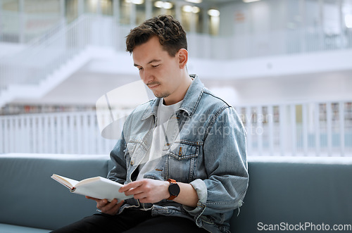 Image of Education, library and man with a book, reading and studying for a test, exam and knowledge. Male, student and academic with journal, research or focus on learning, peace and relax with calm or quiet