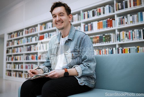 Image of Student man, library portrait and writing on sofa with smile, happy and focus on education at college. University student, pen and notebook for notes, goals and ideas for studying, research and task