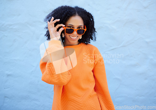 Image of Trendy, portrait and woman with sunglasses by a wall in the city on a vacation or weekend trip. Happy, smile and female with orange, fashion or stylish eyewear in town while on a holiday in Mexico.