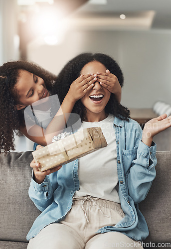 Image of Mothers day, present and surprise of a child with a gift for mom in a living room. Wow, home and mother on a couch with a girl holding eyes closed with happiness and a smile in a house with box