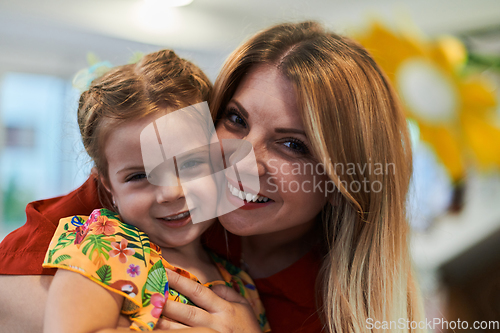 Image of A cute little girl kissing and hugs her mother in preschool