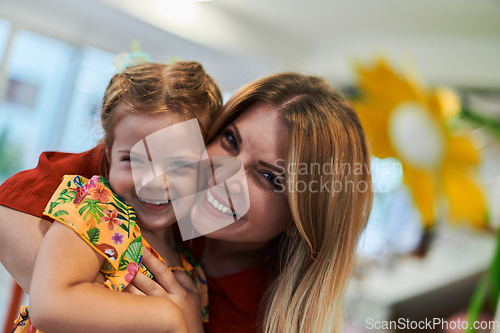 Image of A cute little girl kissing and hugs her mother in preschool