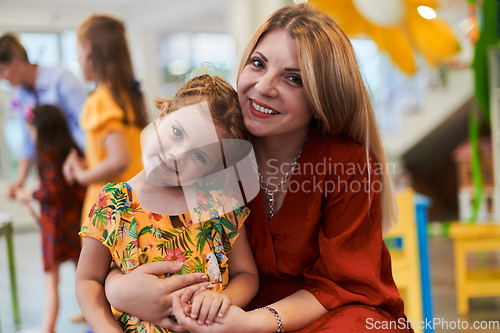 Image of A cute little girl kissing and hugs her mother in preschool